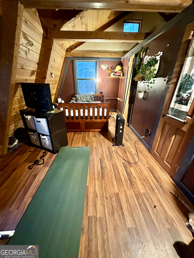 bedroom featuring wooden walls, lofted ceiling with beams, and wood-type flooring