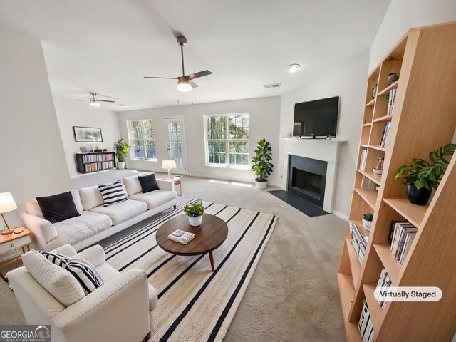 338 Hunterian Pl, Newnan, GA 30265 - living area featuring a fireplace with flush hearth, visible vents, light carpet, baseboards, and ceiling fan