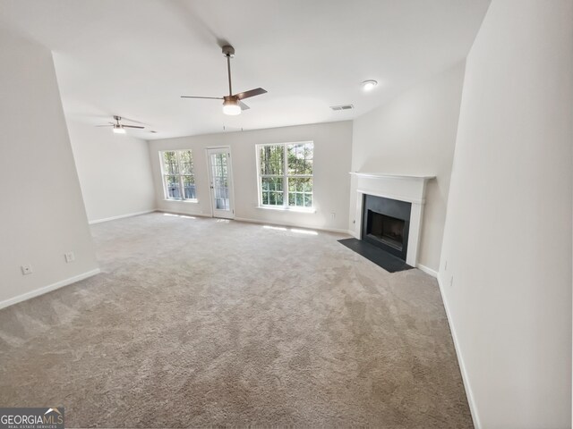 338 Hunterian Pl, Newnan, GA 30265 - unfurnished living room featuring a fireplace with flush hearth, carpet flooring, baseboards, visible vents, and a ceiling fan