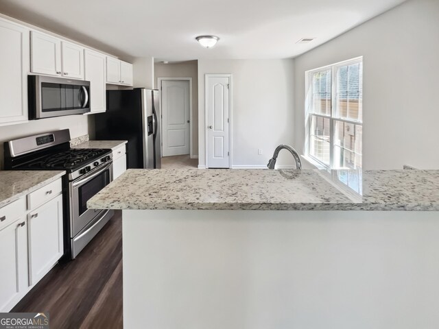 338 Hunterian Pl, Newnan, GA 30265 - kitchen featuring stainless steel appliances, a peninsula, visible vents, white cabinetry, and light stone countertops
