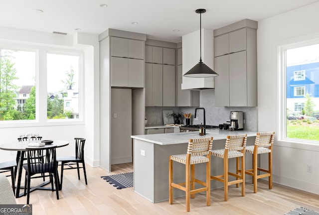 kitchen with a wealth of natural light, tasteful backsplash, kitchen peninsula, and gray cabinets