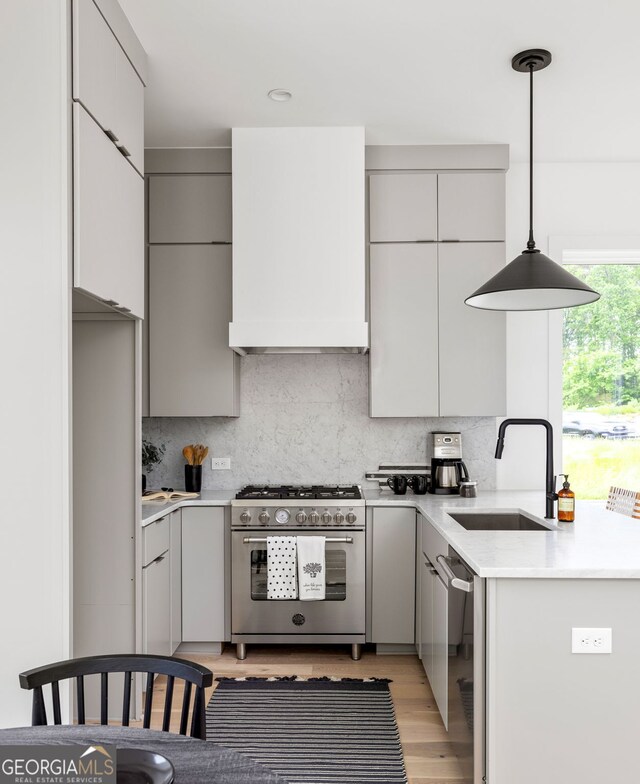 kitchen featuring gray cabinetry, tasteful backsplash, appliances with stainless steel finishes, decorative light fixtures, and sink