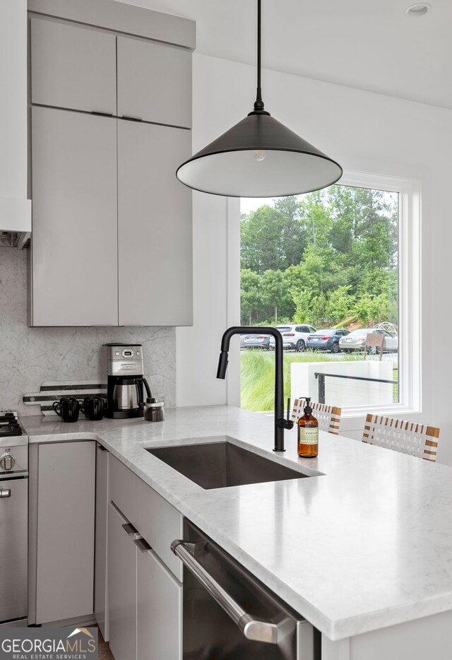 kitchen featuring sink, backsplash, appliances with stainless steel finishes, and decorative light fixtures