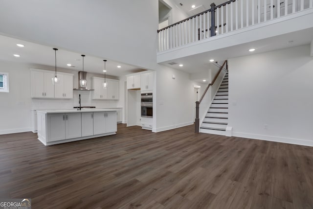 unfurnished living room featuring dark hardwood / wood-style flooring, sink, and a towering ceiling