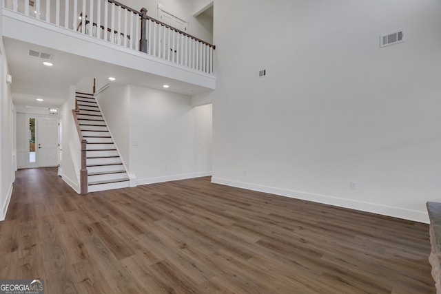 unfurnished living room with a towering ceiling and hardwood / wood-style flooring