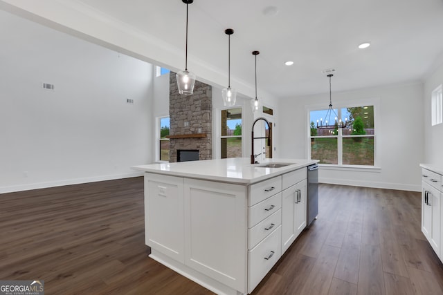 kitchen featuring dark wood-type flooring, a center island with sink, sink, pendant lighting, and white cabinetry