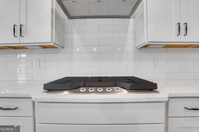 kitchen featuring light stone countertops, white cabinetry, and backsplash