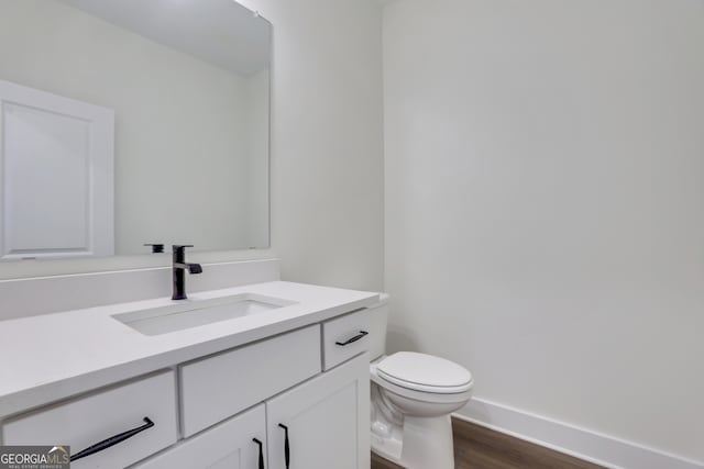 bathroom with wood-type flooring, toilet, and vanity