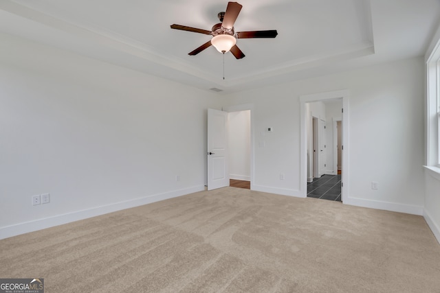 unfurnished bedroom with carpet flooring, ceiling fan, and a raised ceiling