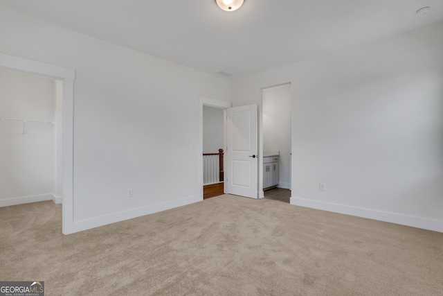 unfurnished bedroom featuring light colored carpet, a closet, and a spacious closet