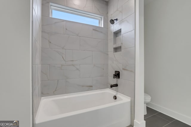 bathroom with tile patterned flooring, tiled shower / bath, and toilet