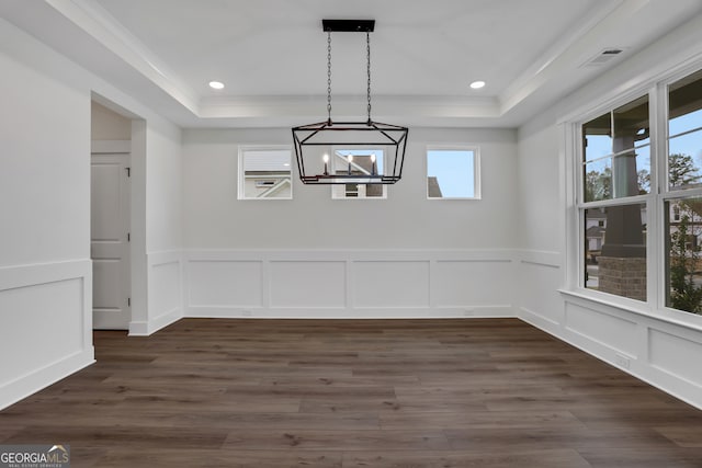 unfurnished dining area with dark hardwood / wood-style flooring, a tray ceiling, an inviting chandelier, and crown molding