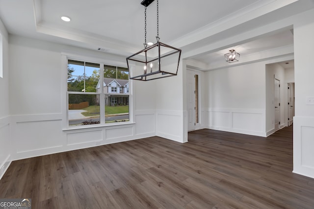 unfurnished dining area featuring dark wood-type flooring, a tray ceiling, an inviting chandelier, and crown molding