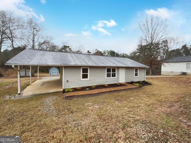 rear view of property with driveway, a lawn, and a carport