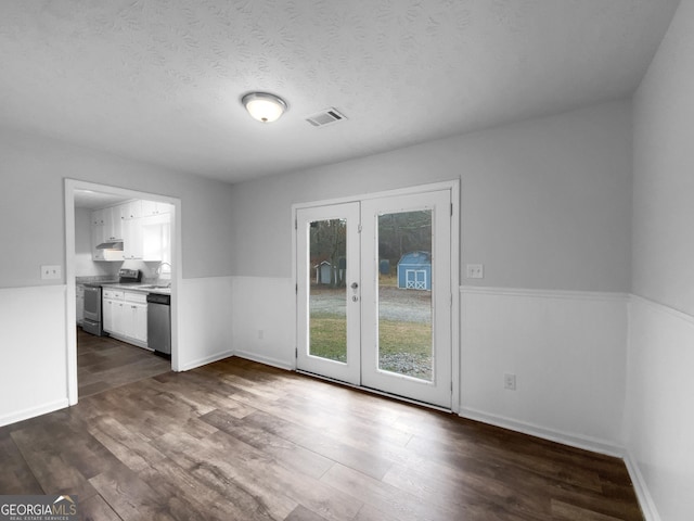 unfurnished dining area with visible vents, dark wood-style flooring, a textured ceiling, french doors, and a sink