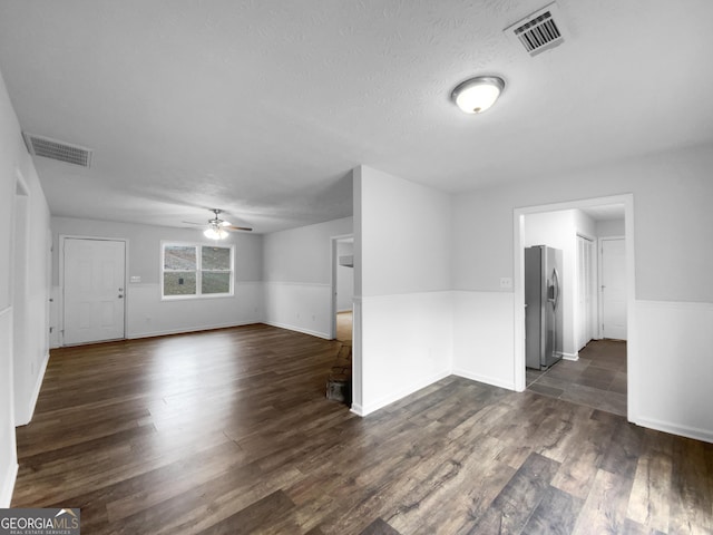 unfurnished room with dark wood-type flooring, visible vents, ceiling fan, and a textured ceiling