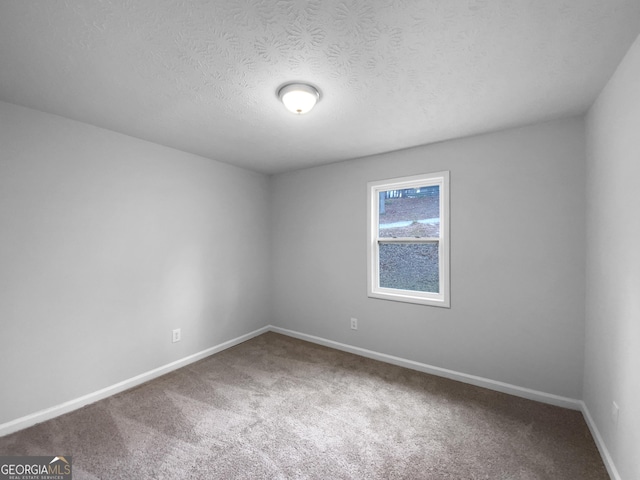 carpeted empty room featuring a textured ceiling and baseboards