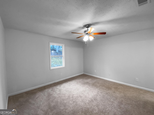 spare room with a textured ceiling, ceiling fan, carpet floors, visible vents, and baseboards