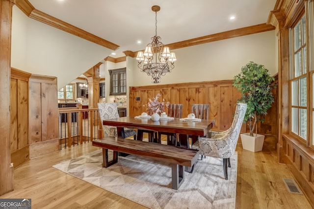 dining room with light hardwood / wood-style flooring, a notable chandelier, a wealth of natural light, and ornamental molding