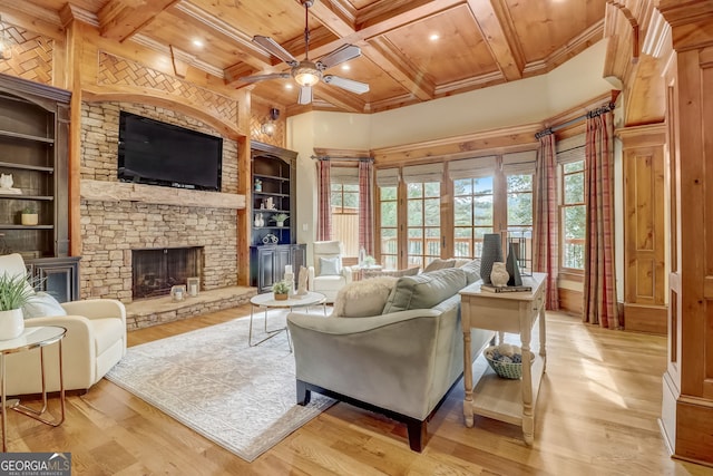 living room with a fireplace, ceiling fan, beamed ceiling, light hardwood / wood-style flooring, and built in shelves