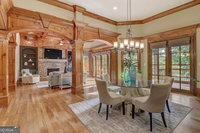 dining space featuring light hardwood / wood-style flooring, decorative columns, a brick fireplace, and a healthy amount of sunlight