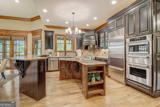 kitchen with a breakfast bar area, light wood-type flooring, built in appliances, and a center island