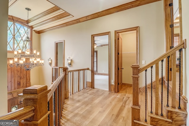 interior space with crown molding, light hardwood / wood-style flooring, ceiling fan with notable chandelier, and a raised ceiling