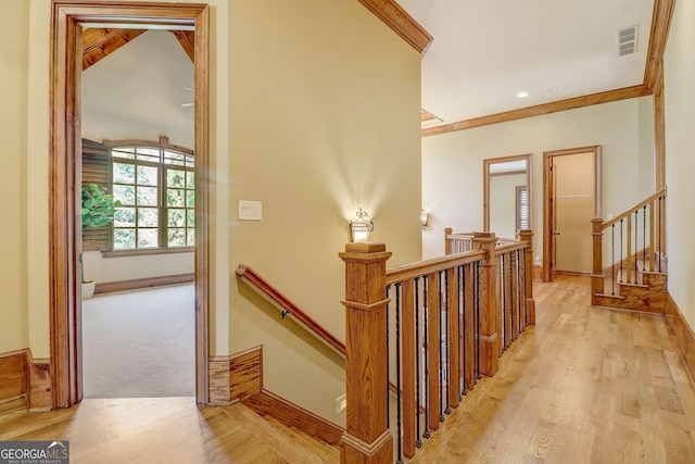 stairs with light hardwood / wood-style floors and ornamental molding