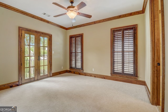 carpeted spare room featuring plenty of natural light, french doors, ornamental molding, and ceiling fan