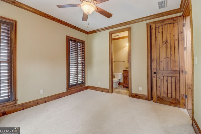 unfurnished bedroom with connected bathroom, light carpet, crown molding, and ceiling fan