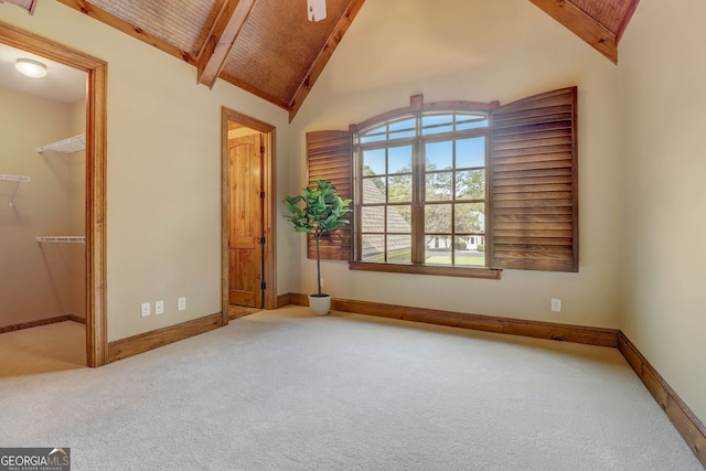 unfurnished bedroom featuring light carpet, high vaulted ceiling, a spacious closet, and beamed ceiling