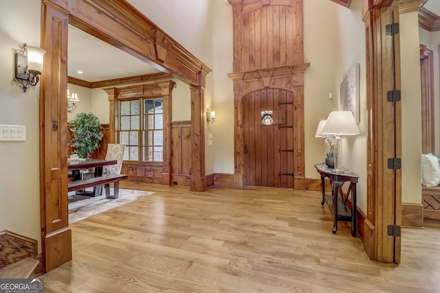 foyer with ornamental molding, a notable chandelier, and light wood-type flooring