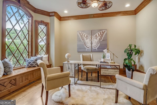 living area featuring an inviting chandelier, light hardwood / wood-style flooring, and ornamental molding