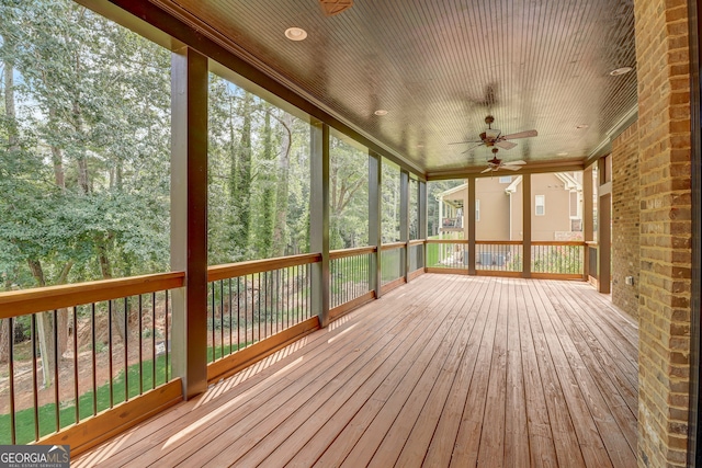 unfurnished sunroom with ceiling fan, wood ceiling, and a wealth of natural light