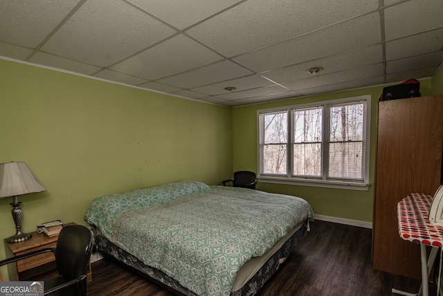 bedroom with a drop ceiling and dark hardwood / wood-style flooring