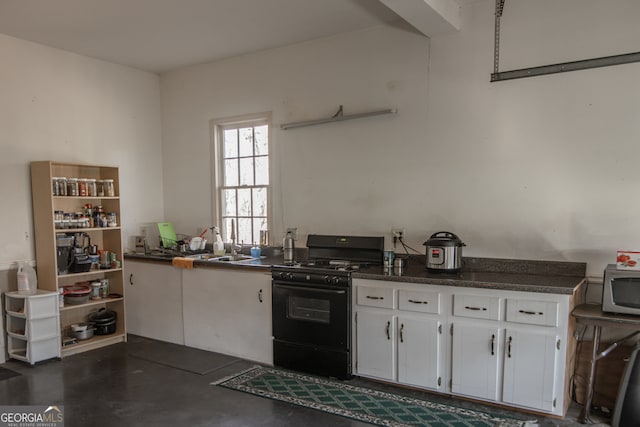 kitchen with black gas stove, white cabinetry, and sink