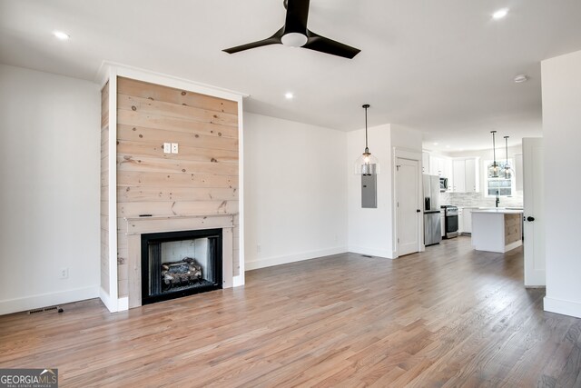 unfurnished living room with ceiling fan, sink, a fireplace, and light hardwood / wood-style floors