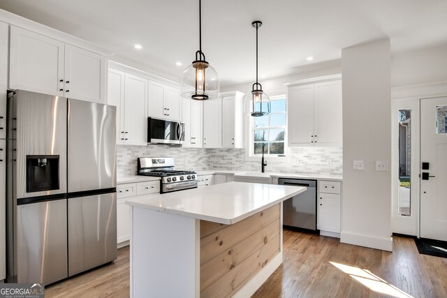 kitchen with white cabinets, a kitchen island, light hardwood / wood-style flooring, and appliances with stainless steel finishes