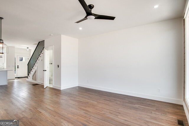 unfurnished room featuring ceiling fan with notable chandelier and hardwood / wood-style floors