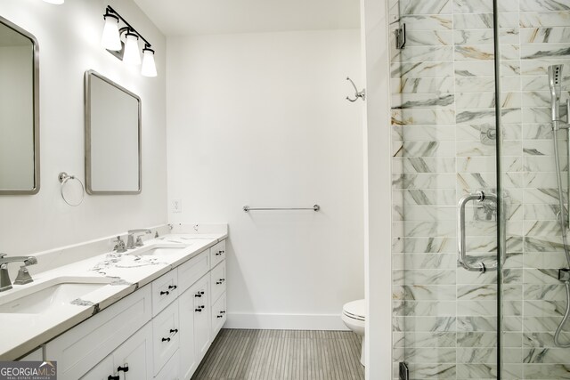 bathroom with tile flooring, dual sinks, toilet, vanity with extensive cabinet space, and an enclosed shower