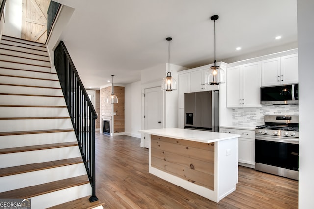 kitchen with a kitchen island, light wood-type flooring, white cabinetry, and stainless steel appliances