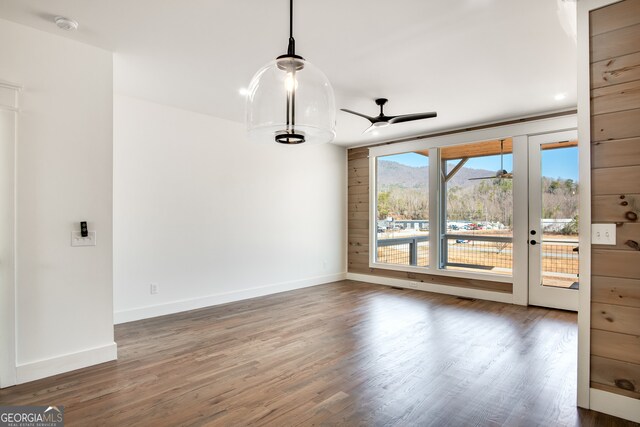 empty room featuring french doors, ceiling fan, and dark wood-type flooring