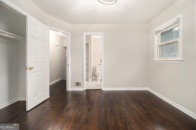 unfurnished bedroom featuring a walk in closet, hardwood / wood-style floors, and ensuite bath