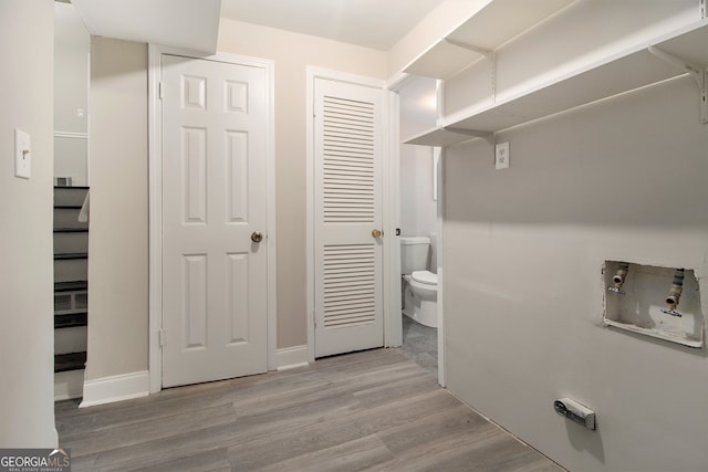 clothes washing area with light hardwood / wood-style floors and washer hookup