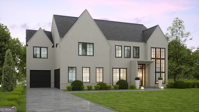 view of front facade featuring a lawn, driveway, an attached garage, and stucco siding