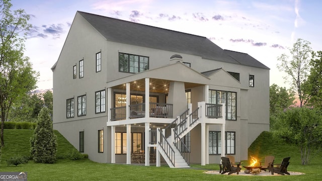 rear view of house with a yard, a fire pit, a balcony, and stairs