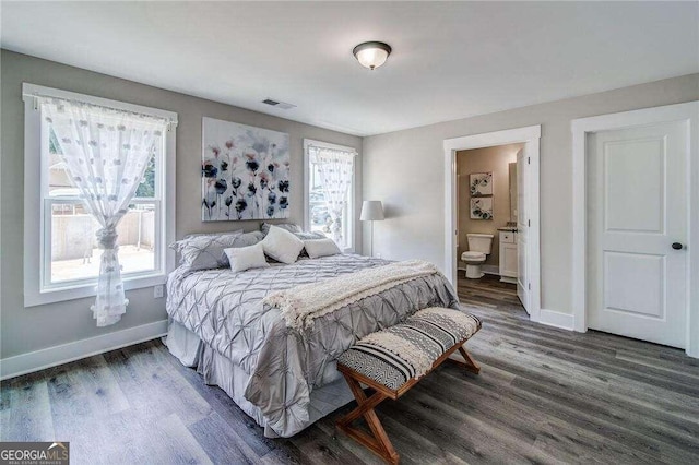 bedroom featuring ensuite bath, dark hardwood / wood-style flooring, and multiple windows