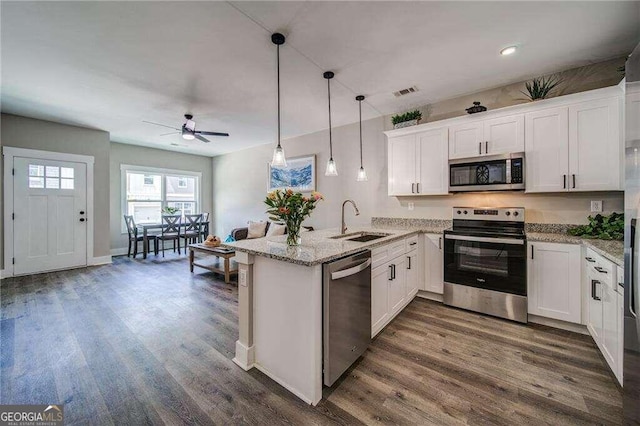 kitchen featuring dark hardwood / wood-style flooring, appliances with stainless steel finishes, white cabinetry, and pendant lighting