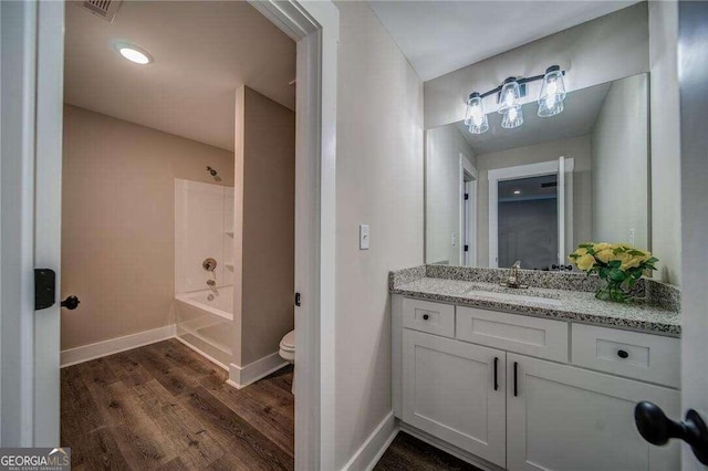 full bathroom with vanity with extensive cabinet space, wood-type flooring, toilet, and shower / tub combination