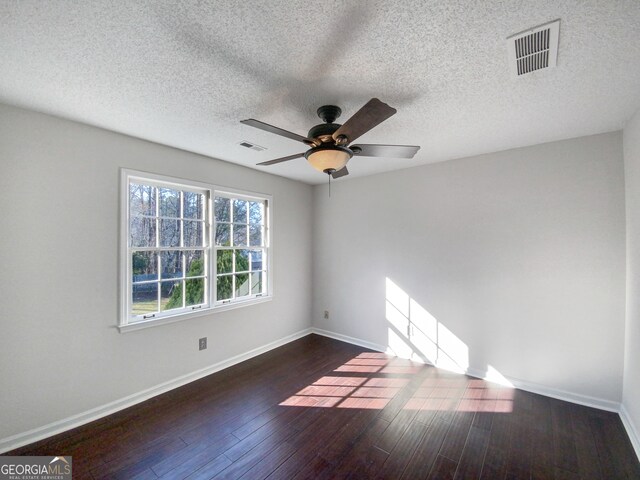 unfurnished room with ceiling fan, a textured ceiling, and dark wood-type flooring